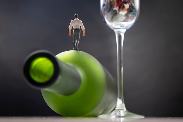 미니어처 사람들은 사회의 알코올 중독 문제에 대한 개념의 와인 잔 바닥에 있는 알코올 중독자입니다.