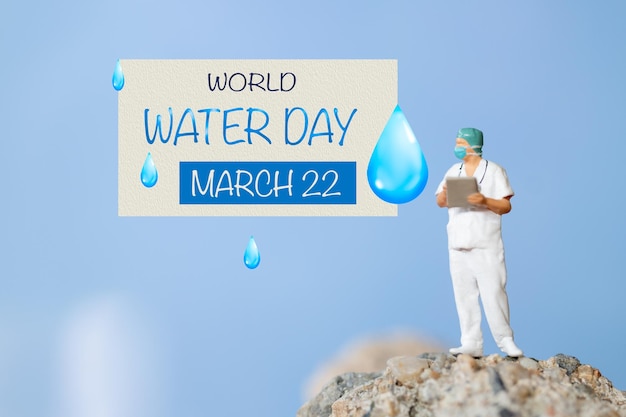 Miniature people Doctor checking text World Water Day on paper while standing atop a rock