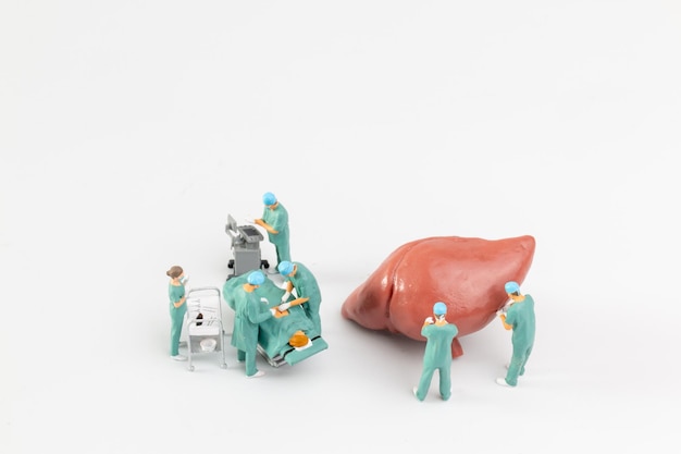 Miniature people Doctor and nurse medical team are performing surgical operation at emergency room on white background