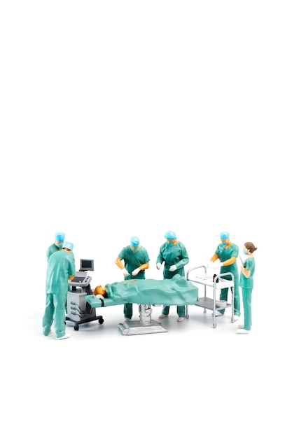 Фото Миниатюрные люди доктор выполняет операцию на пациенте на белом фоне
