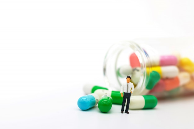 Photo miniature people: doctor standing with drugs. health care and business concept.