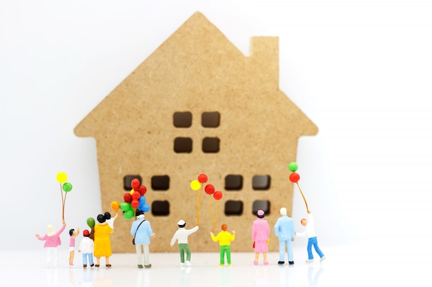 Miniature people: family and children enjoy with colorful balloons and house, happy family day concept.