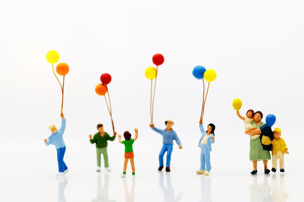 Photo miniature people, family and children enjoy with colorful balloons.