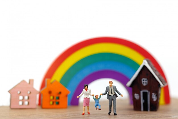 Persone in miniatura: famiglia e bambini si divertono con la casa e l'arcobaleno.