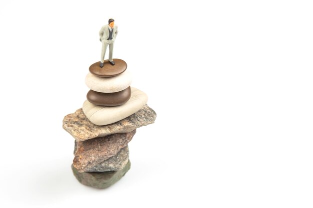 Miniature people the figure of a man stands on top of the stones concept of achievements in life and success in business