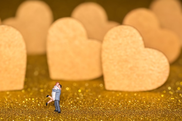 Miniature people and golden hearts. A loving couple on a radiant background.