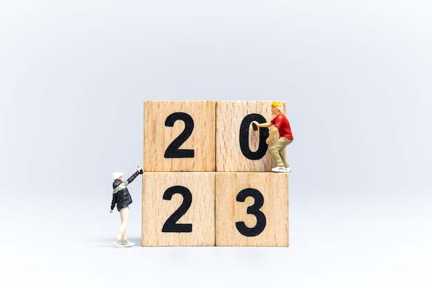 ミニチュアの人々の落書きアーティストが木製のブロックに番号2023をスプレー