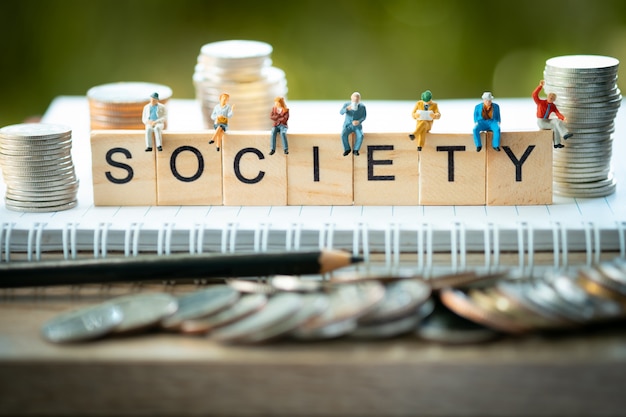 Photo miniature people, group of business people sitting on wooden blocks with society word.