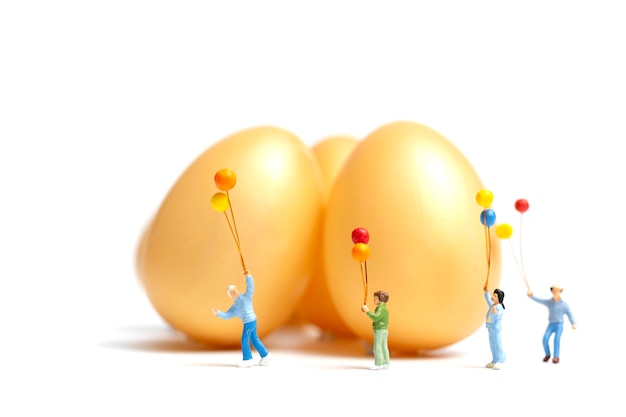 Miniature people: Happy family holding balloon celebrating Easter