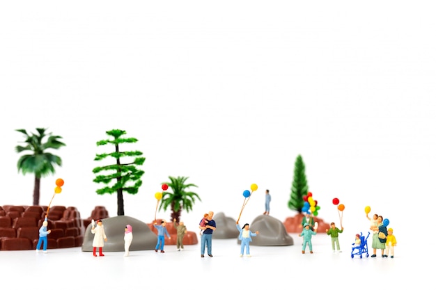 Persone in miniatura: famiglia felice con palloncino nel parco