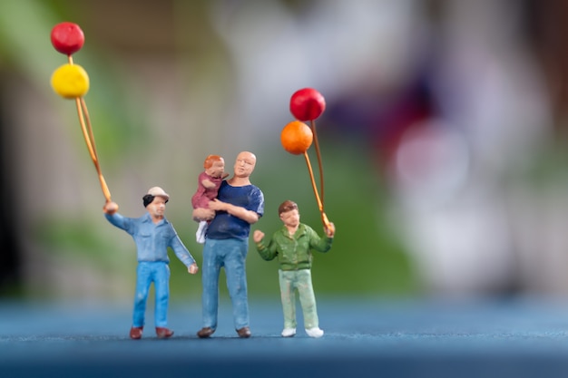 Persone in miniatura: famiglia felice con palloncino nel parco