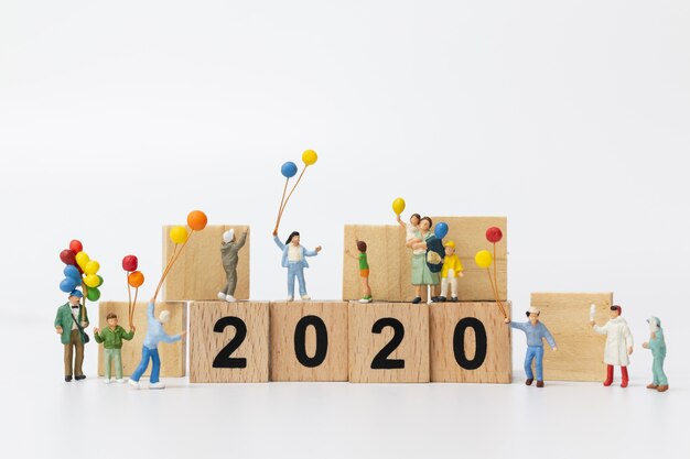 Miniature people: Happy family holding balloon on wooden block number 2020 