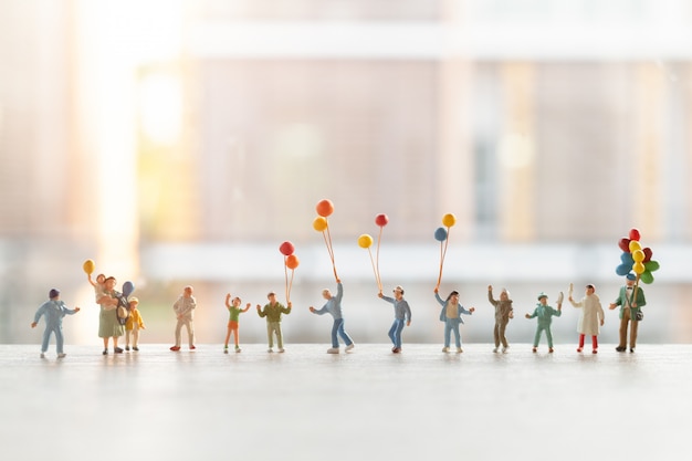 Photo miniature people : happy family walking with balloons