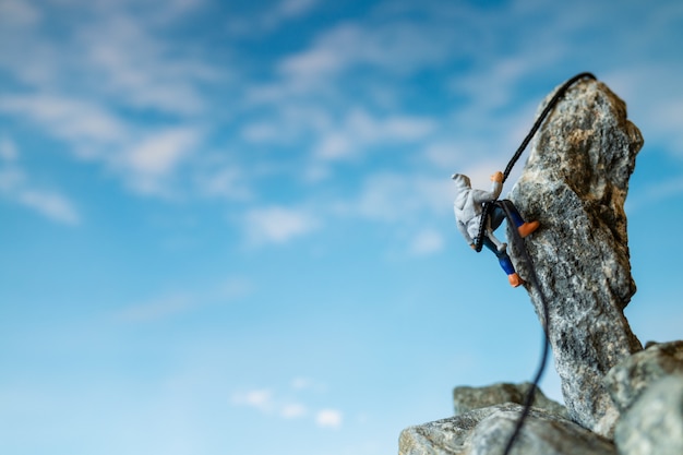 Miniature people: Hikers climbing up on the rock . Sport and leisure concept.