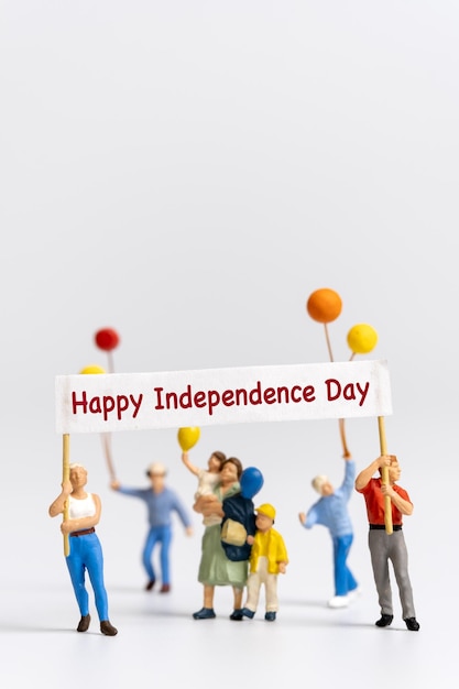 Miniature people holding flags with word Happy Independence day