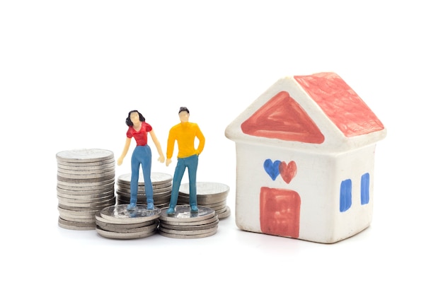 Miniature people,husband and wife standing with house and stack coins. saving and loan concept. 