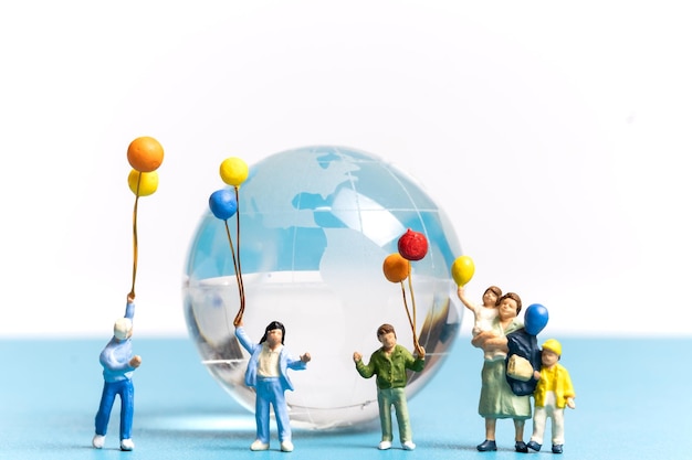 Miniature people kid holding balloon with crystal Globe World environment day concept