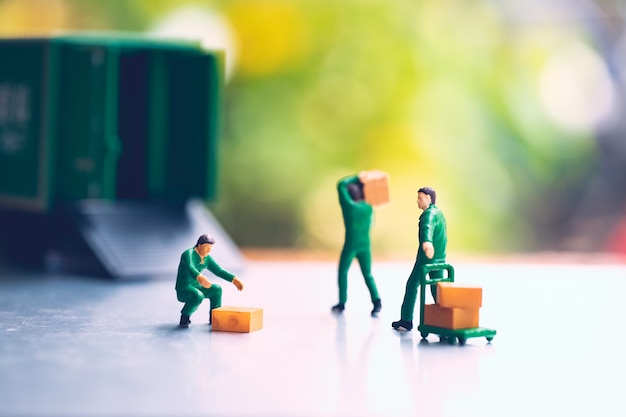 Persone in miniatura, uomo che trasporta una scatola che utilizza per la logistica e il concetto di business