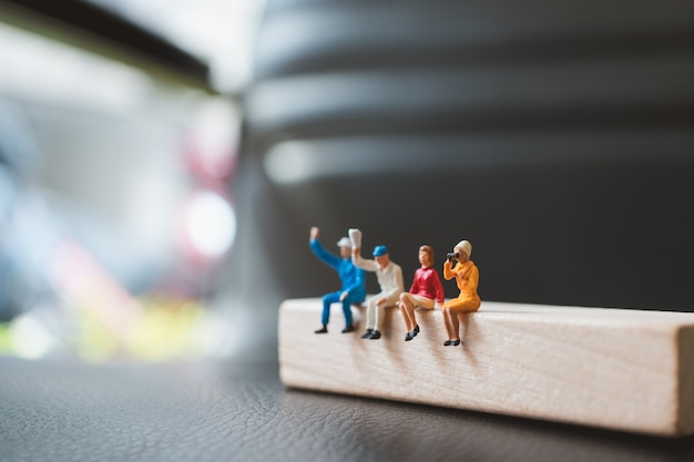 Miniature people, man and woman sitting on wooden block using as business concept