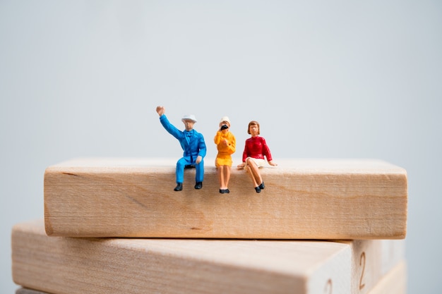 Foto gente miniatura, uomo e donna che si siedono sul blocco di legno usando come concetto di affari e sociale