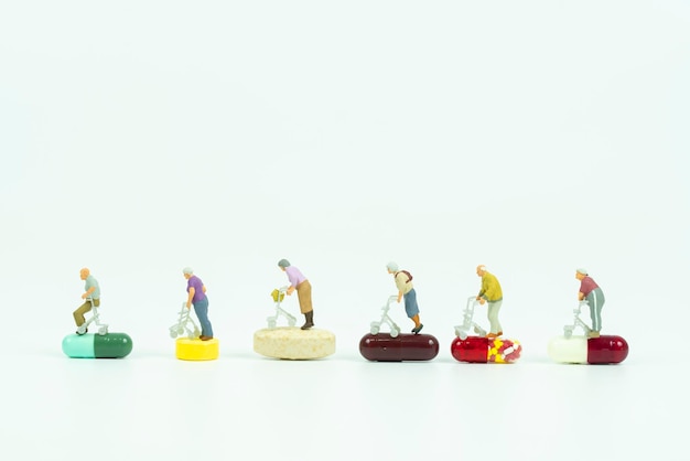 Foto persone in miniatura su farmaci concetto di assistenza sanitaria per anziani