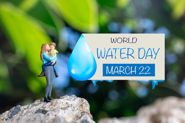 miniature people mother holding son in the arms and words written on paper world water day