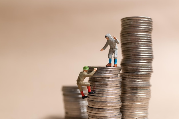 Miniature people Mountain climber ascending the coin stack