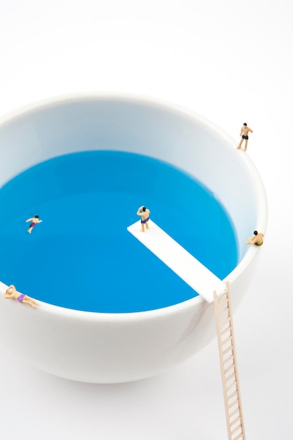 Photo miniature people in mug cup swimming pool