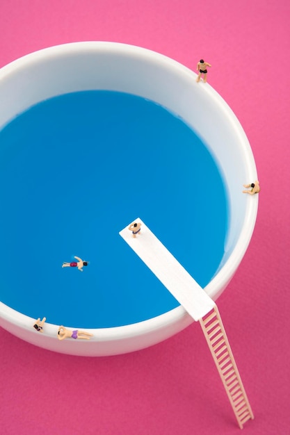 miniature people in mug cup swimming pool