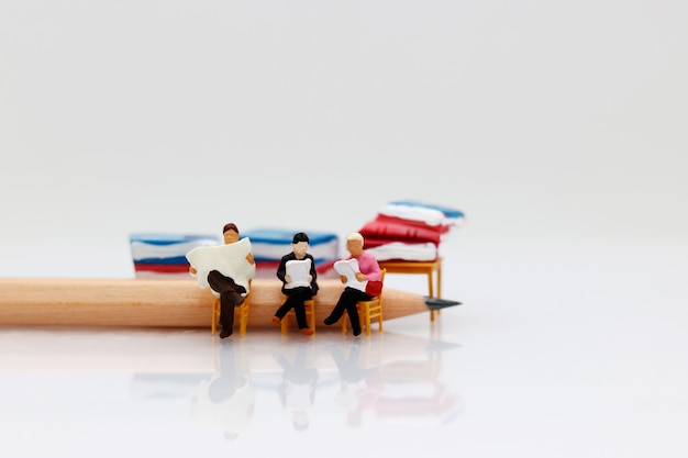 Miniature people reading  book with pencil, education concept.