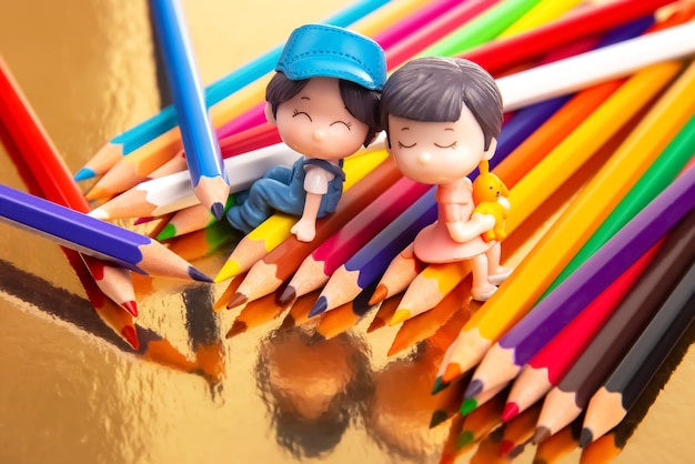 Foto la coppia romantica di persone in miniatura si siede su matite colorate