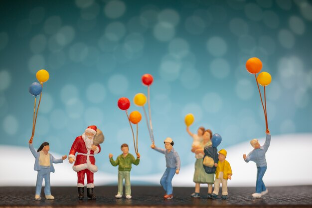 Miniature people: Santa Claus and children holding balloon