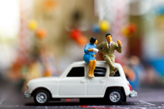 Miniature people sitting on the car