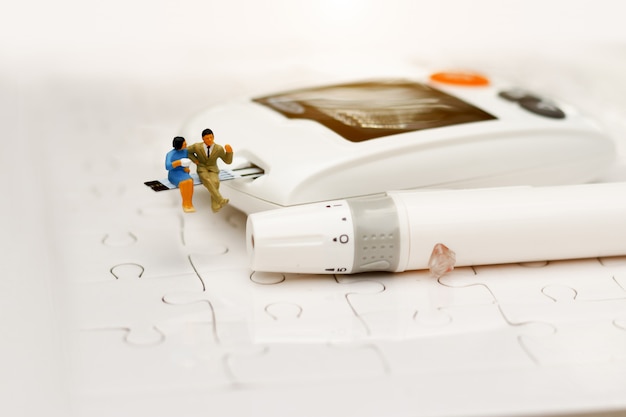 Miniature people sitting on a glucose meter of diabetes ,  health care concept.