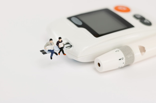 Miniature people sitting on a glucose meter of diabetes ,  health care concept.