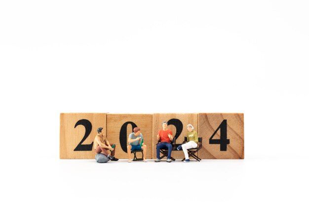 Miniature People sitting On Wooden Block Number 2024