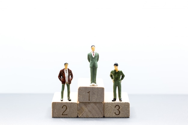 Miniature people small figures businessmen stand on wooden podium