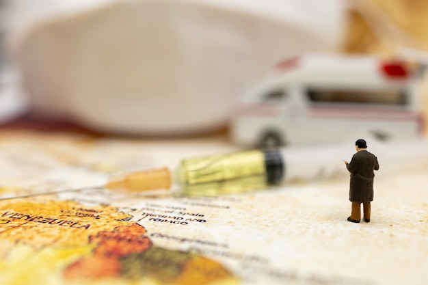 Photo miniature people stand on world map with ambulance car, medical mask and syringe of covid-19 vaccine . vaccine and healthcare medical concept.