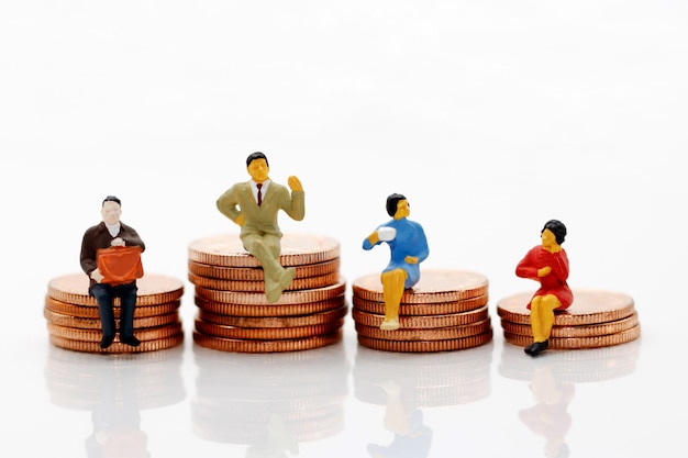 Miniature people standing on coins