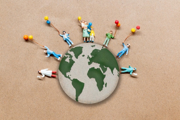 Miniature people standing on the globe with paper background