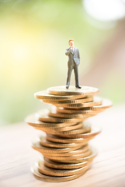 Miniature people standing on stack of coin