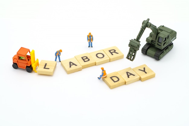 Miniature people standing with wood word Labor Day