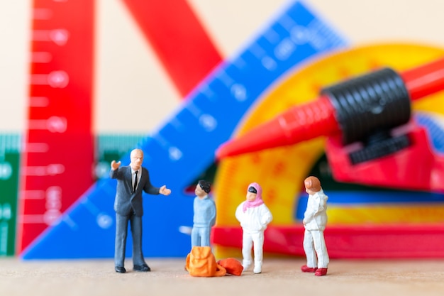 Foto persone in miniatura studente e insegnante con strumenti di cancelleria, concetto di ritorno a scuola.