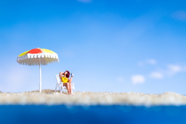 Miniature people sunbathing on The baech with blue sky , Summer time concept