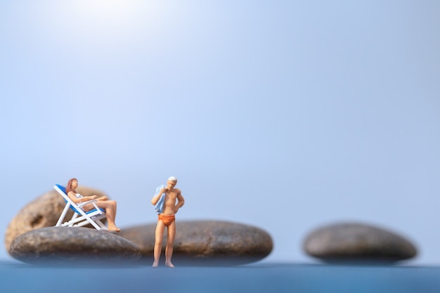 Miniature people sunbathing on The beach , Summer time concept