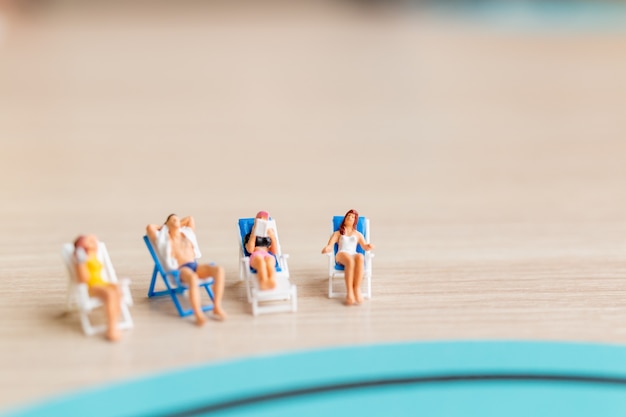 Miniature people sunbathing on The beach , Summer time concept