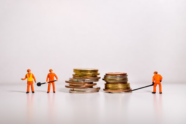 Miniature people, technician working on stack coins 