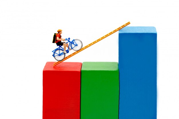 Miniature people: Traveler riding bicycle on wood ladder with growth graph.