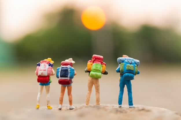 Miniature people : Traveler with backpack walking on the rock 