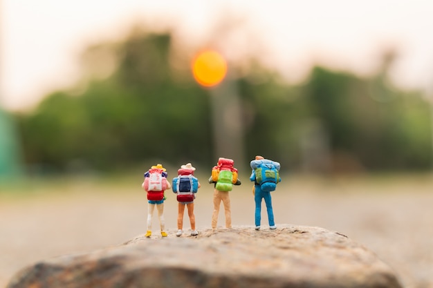 Miniature people : Traveler with backpack walking on the rock 